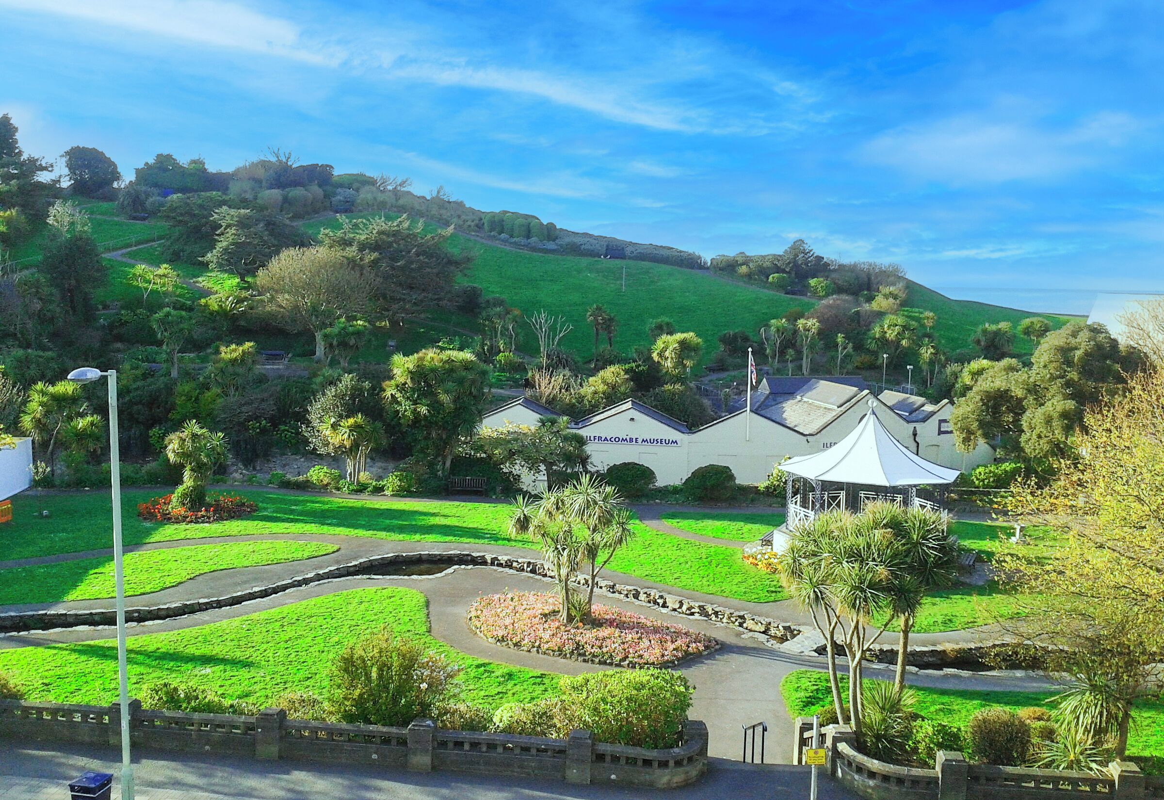 A museum with a white building and a dome-shaped pavilion surrounded by landscaped gardens and a curved road.
