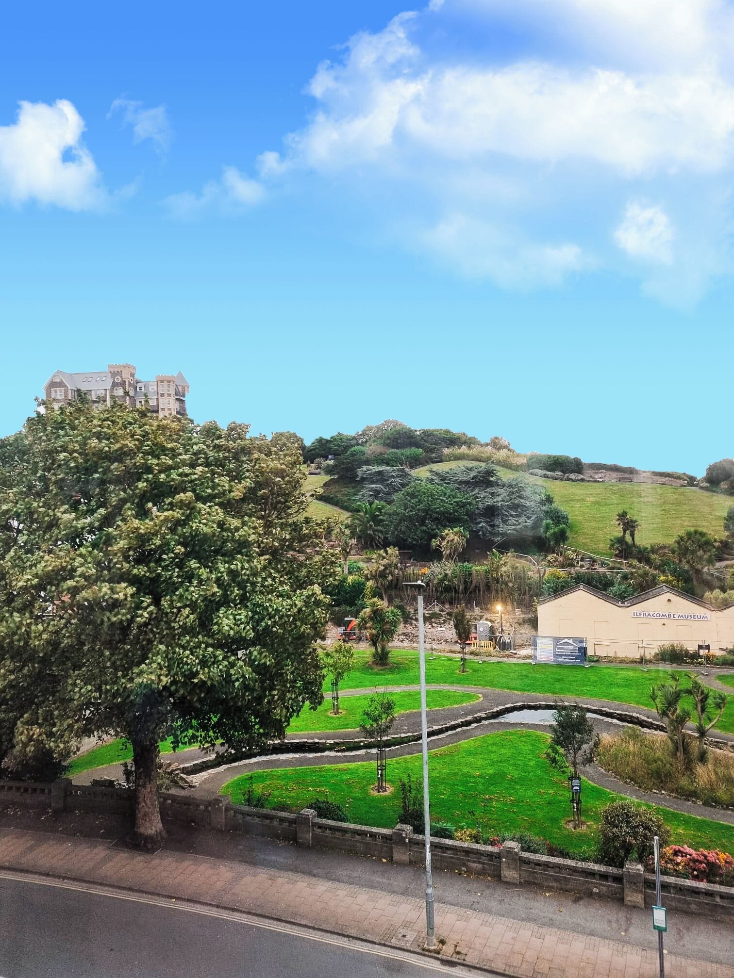 A view of a museum complex with a large building labeled "ILFRACOMBE MUSEUM" and a castle-like structure in the background.
