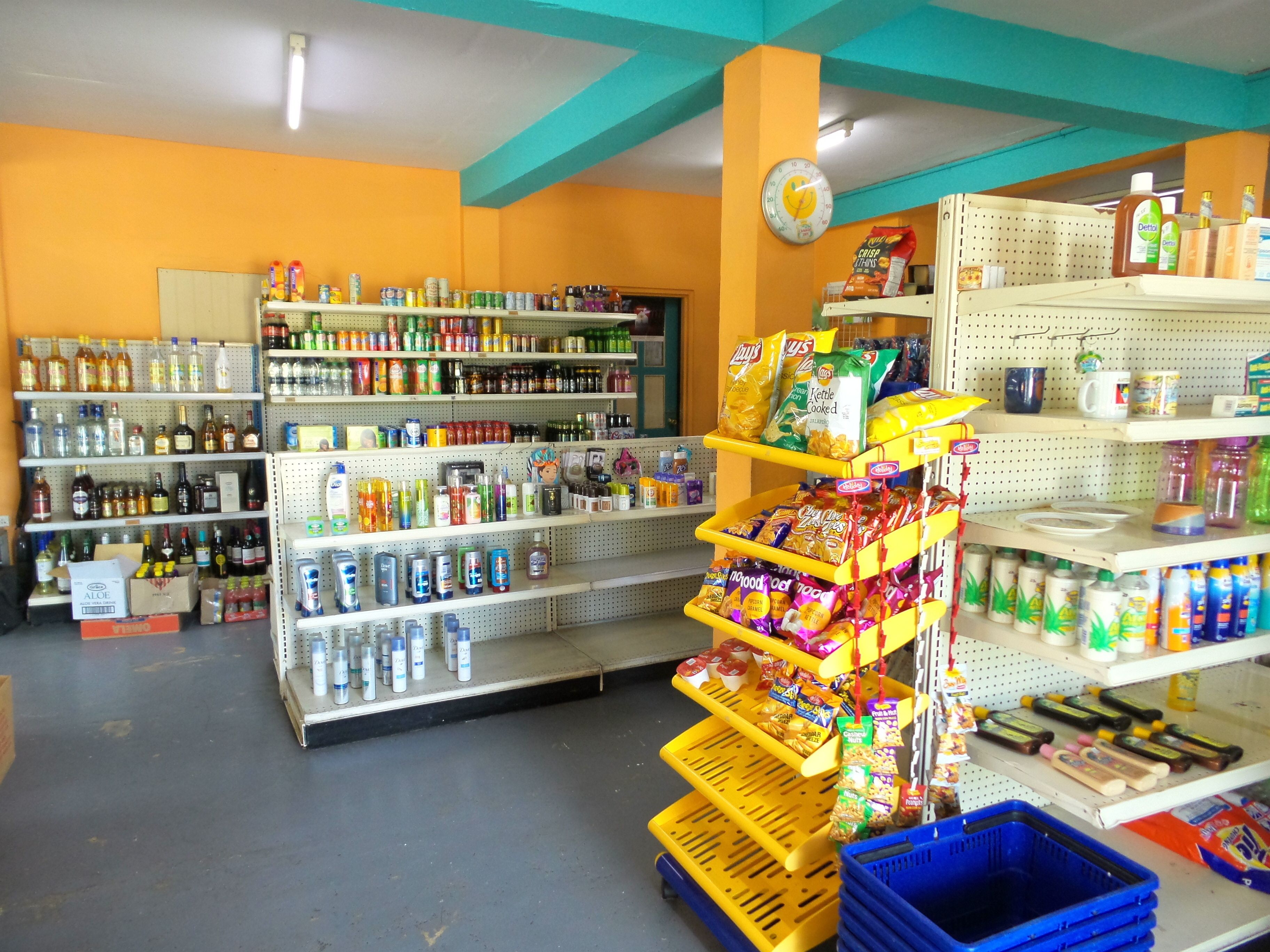 Interior de un supermercado con estantes llenos de diversos productos, entre ellos, snacks, bebidas y artículos para el hogar.