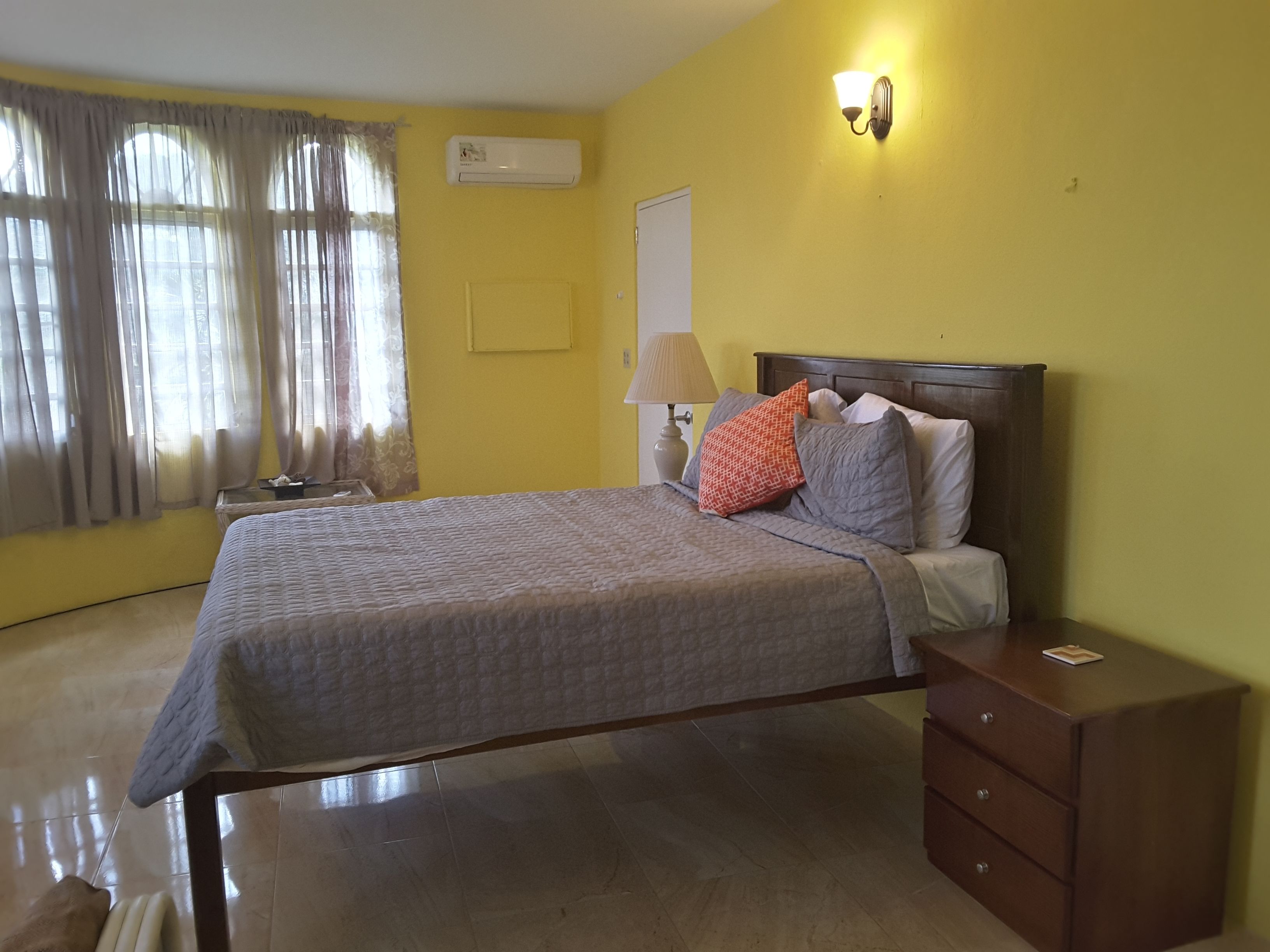 A bedroom with a bed, a nightstand, a lamp, and a dresser.