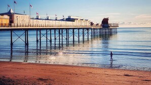 A pier extending into calm waters with buildings and flags on it. - The Esplanade Hotel by Compass Hospitality (Paignton)