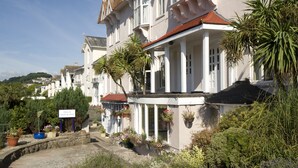 A building with a white facade, multiple windows, and a balcony with hanging flower baskets. - The Esplanade Hotel by Compass Hospitality (Paignton)