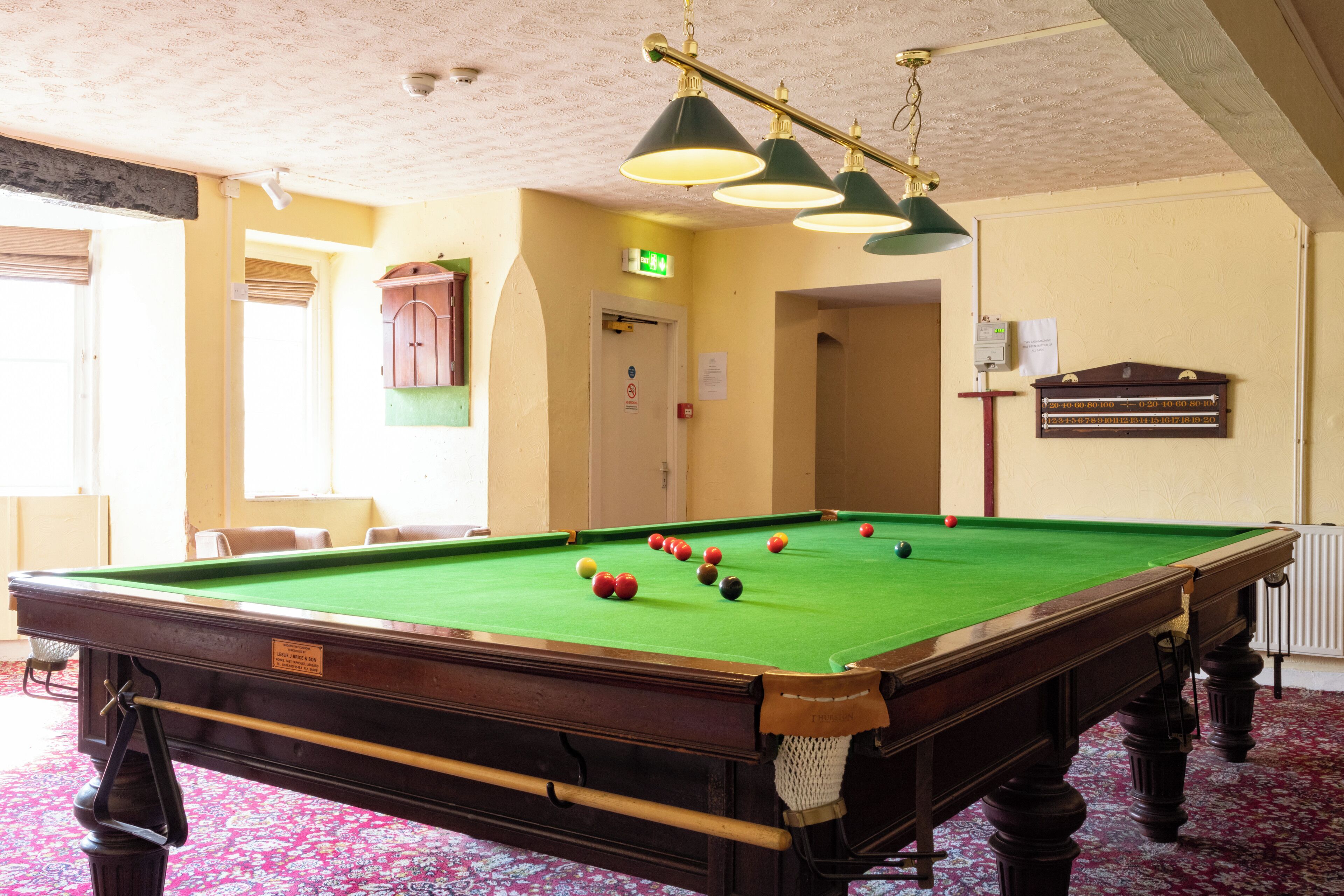 A pool table with balls, a green felt surface, and overhead lighting.