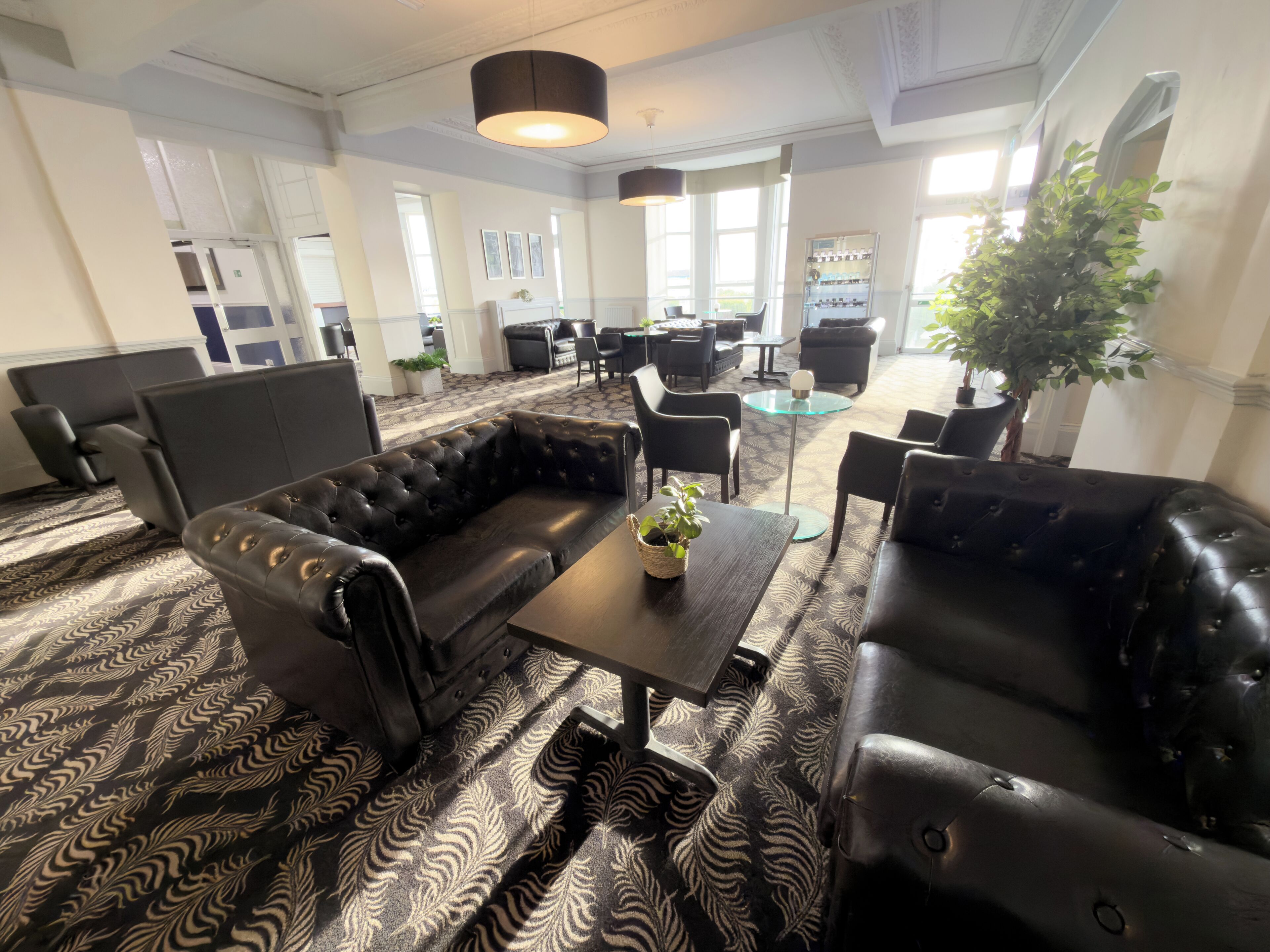 A modern lounge area with leather sofas, a glass coffee table, and a patterned carpet.