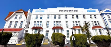 A hotel with a prominent Esplanade Hotel sign, multiple floors, and a red-roofed entrance.