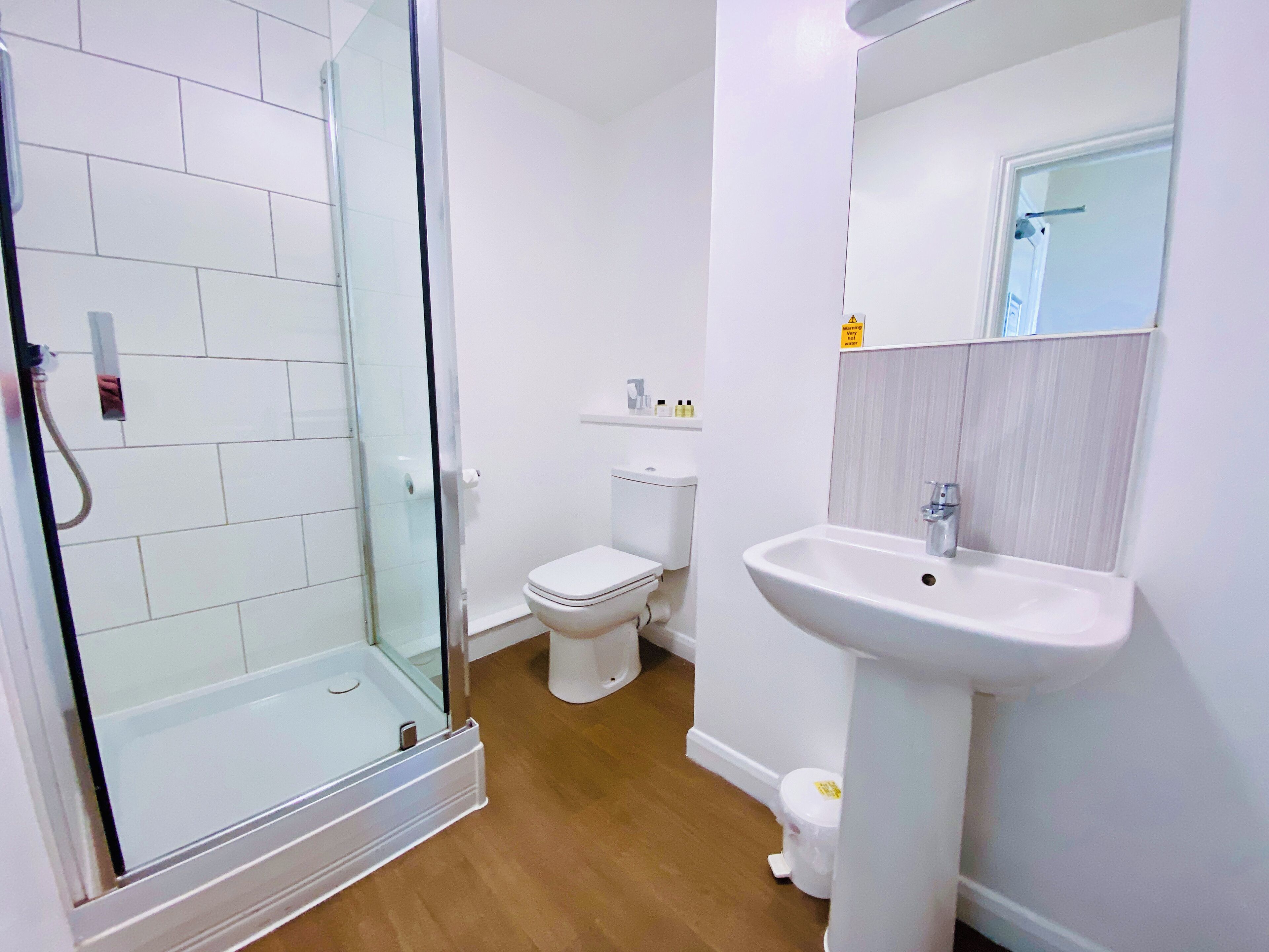 A bathroom with a glass shower enclosure, a toilet, and a sink.