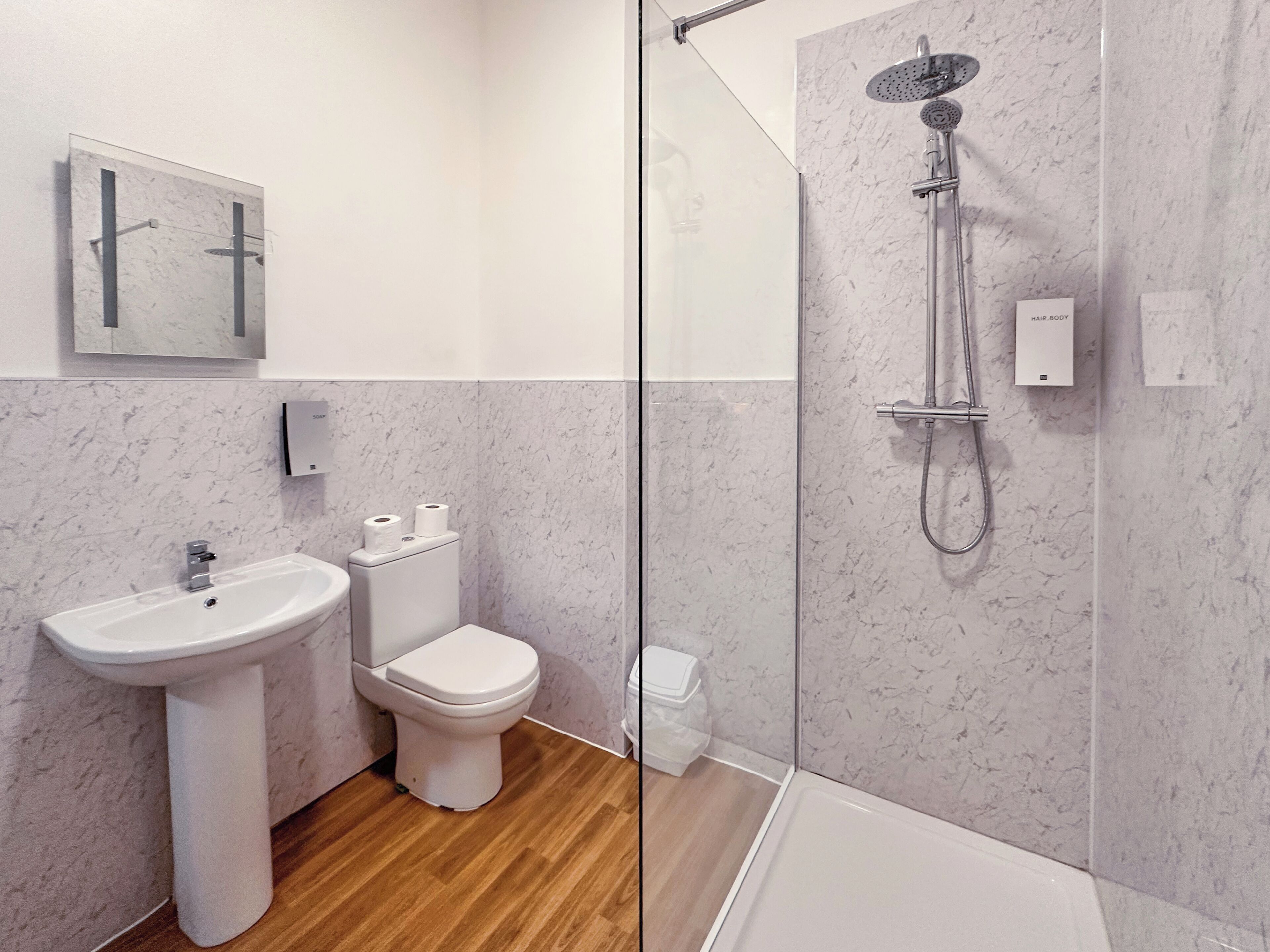 Une salle de bain moderne équipée d’un lavabo, de toilettes et d’une douche.