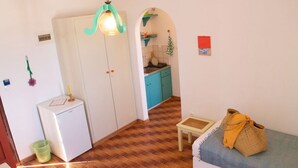 Una cocina compacta con armarios color turquesa, un refrigerador blanco y una pequeña mesa de comedor con un bolso amarillo.