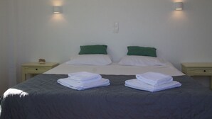 Una cama bien hecha con dos almohadas, dos mesitas de noche y una lámpara de pared.