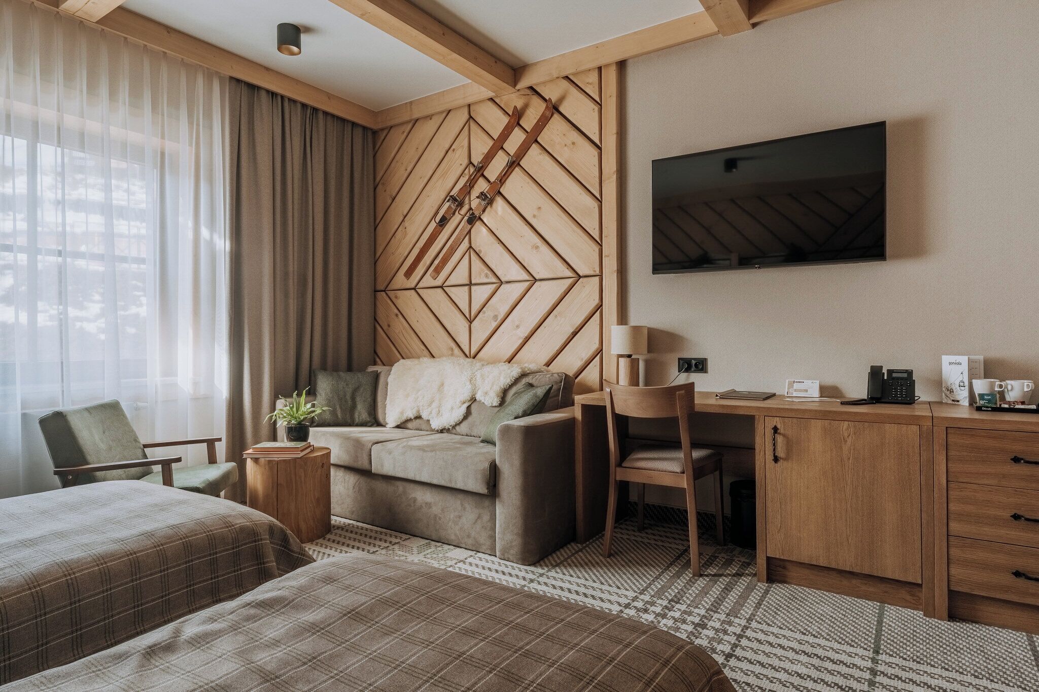 Ein Hotelzimmer mit Bett, Sofa, Schreibtisch und Fernseher.