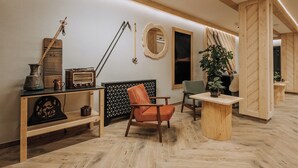 Ein modernes Interieur mit Holzboden im Fischgrätmuster, einem Holzstuhl, einem kleinen Tisch und einem Spiegel an der Wand.