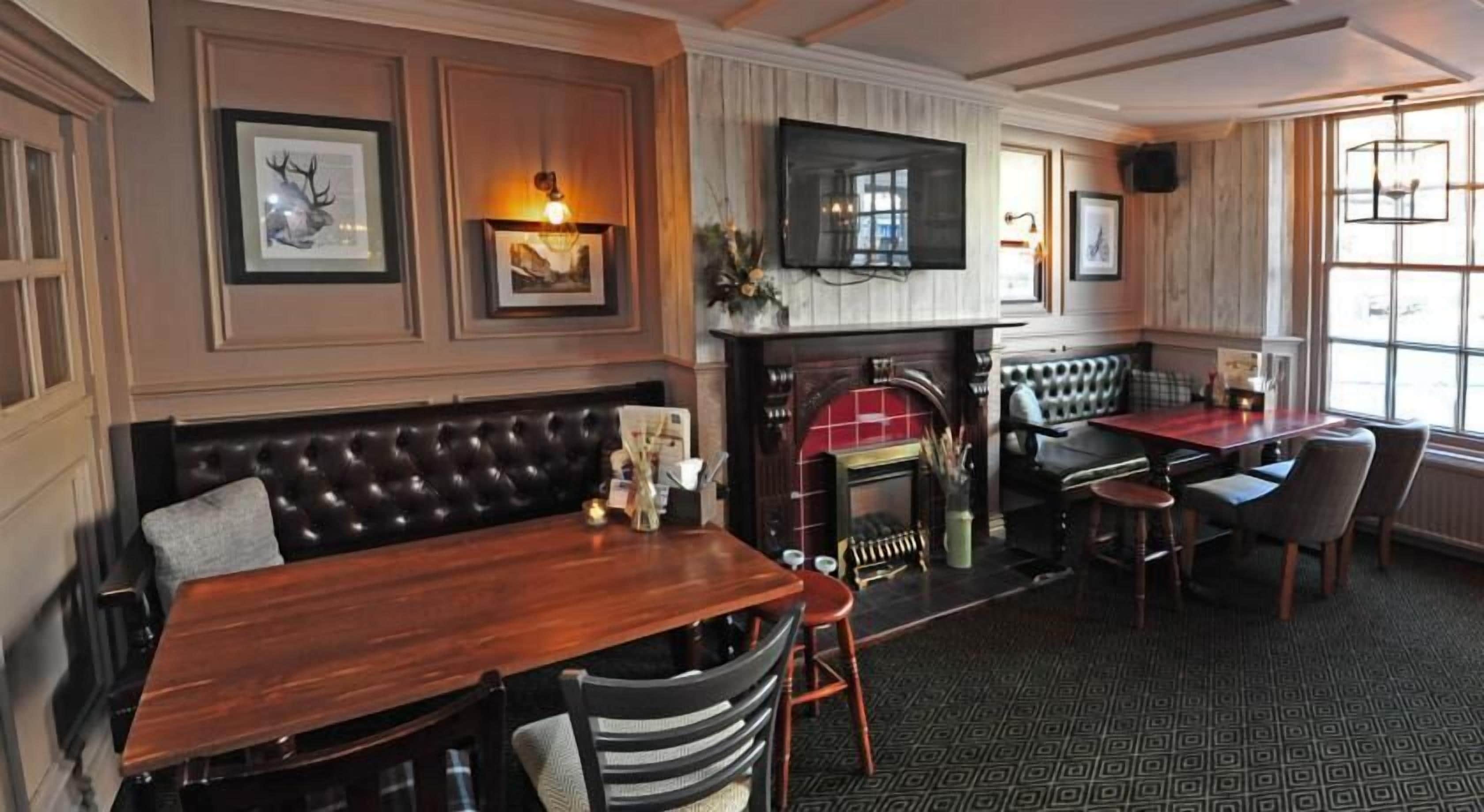 A cozy pub with a wooden bar, a fireplace, and comfortable seating.