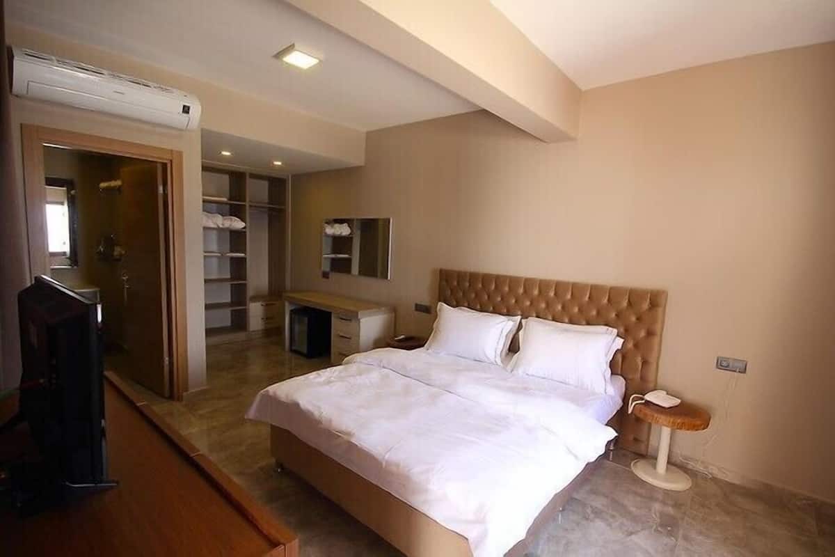 A bedroom with a large bed, a desk, and a wardrobe.