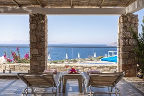 A terrace with stone pillars, a table with a glass of wine, and a view of the sea and mountains. - Vega Aparts (Bodrum)