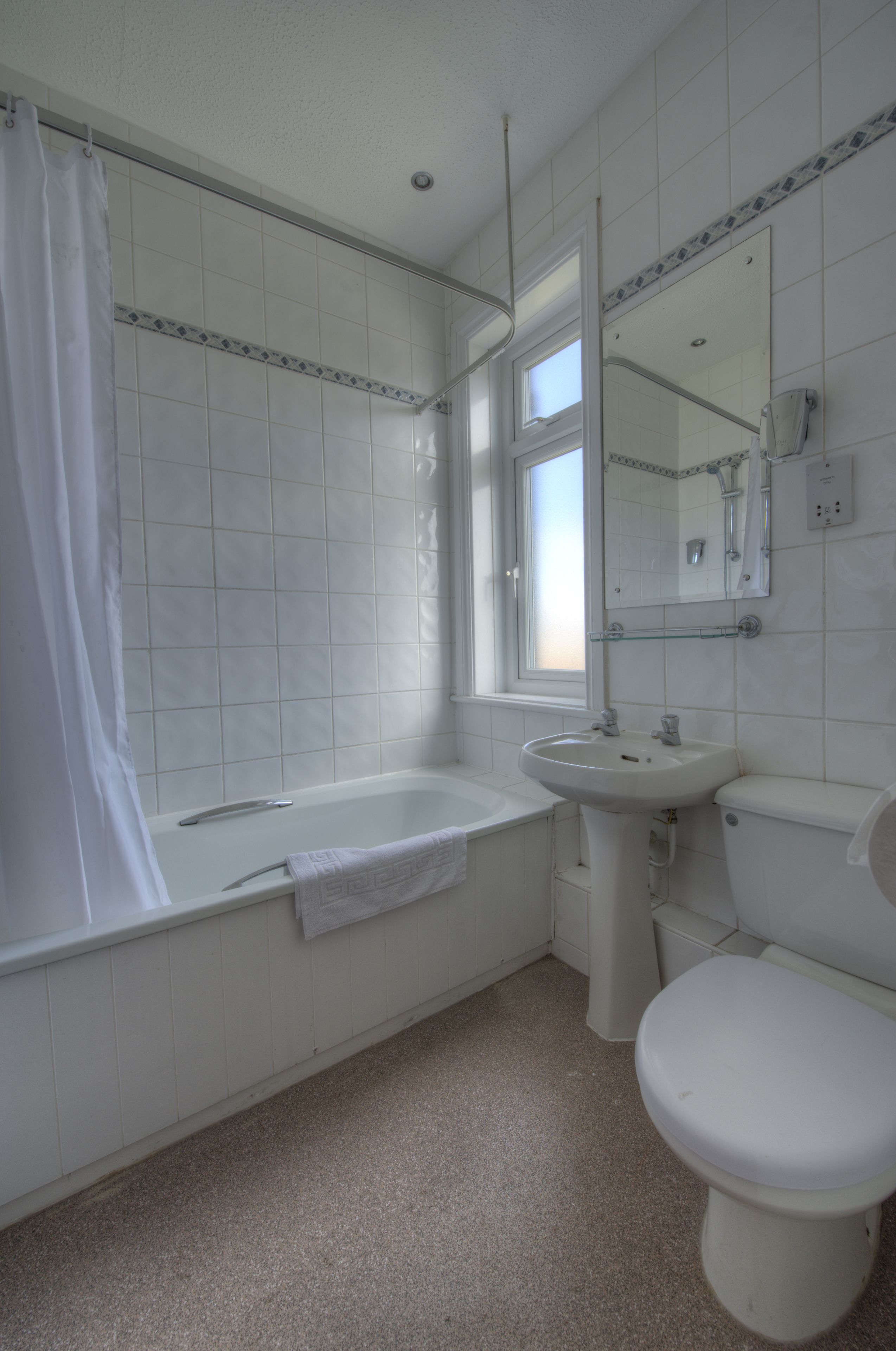 A bathroom with a bathtub, sink, toilet, and a window.
