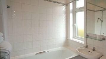 Une salle de bain avec une baignoire, un lavabo et un miroir.