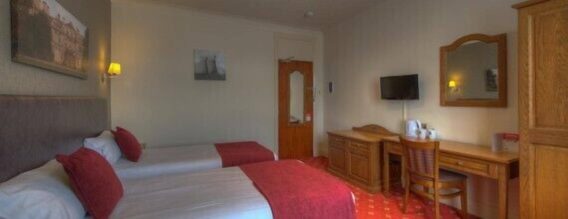 A hotel room with two beds, a desk, a chair, a television, and a mirror.