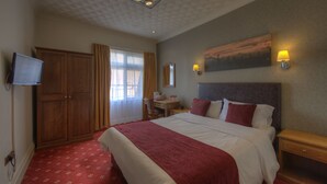 A hotel room with a large bed, a desk, a chair, a television, and a painting on the wall. - Royal Hotel By Greene King Inns (Scunthorpe)