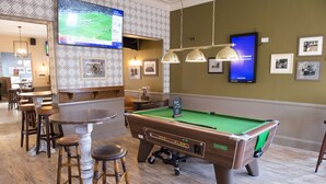 A billiards table, bar stools, a pool table, and a television displaying a sports game. - Royal Hotel By Greene King Inns (Scunthorpe)