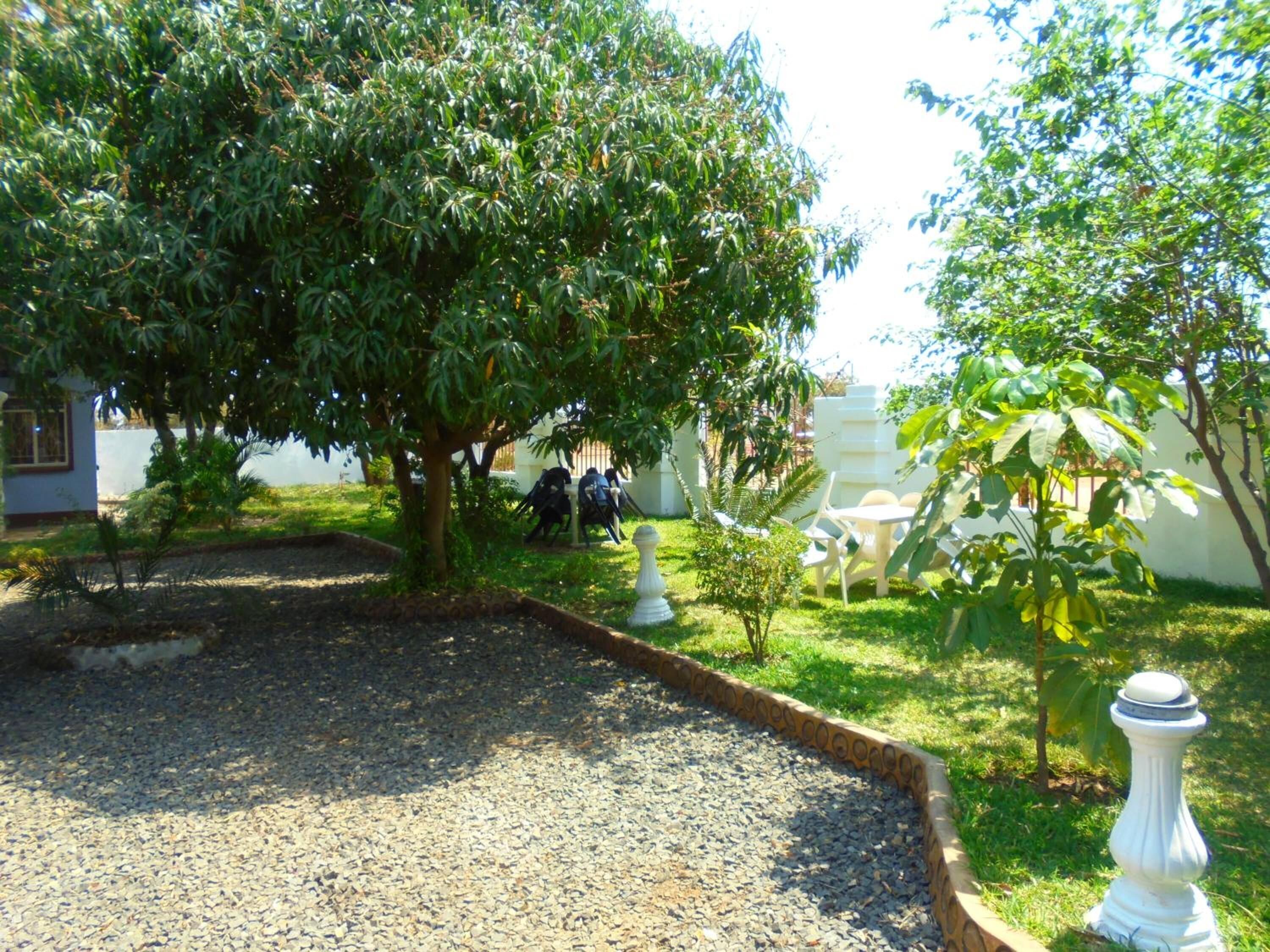 Un jardín con zona de grava, cerca blanca y área de estar con sillas.