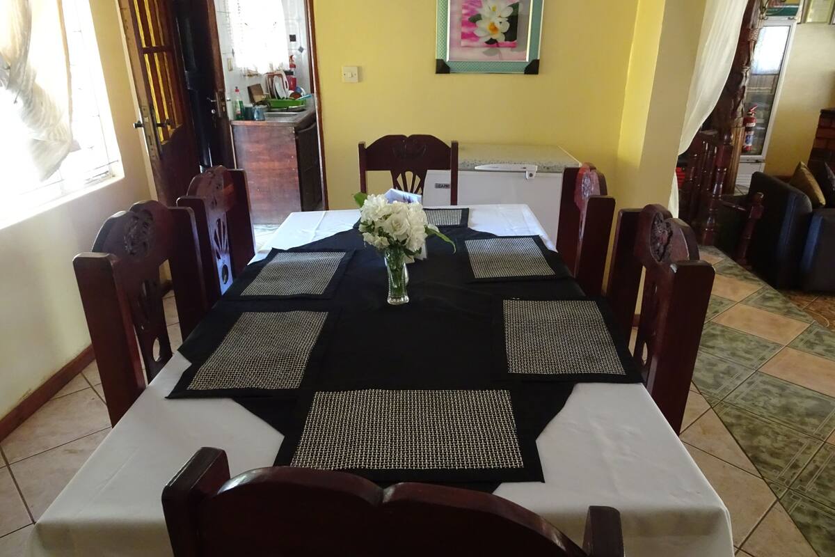 A dining table set with placemats, chairs, and a vase of flowers.