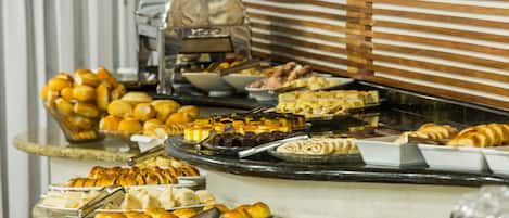 A buffet with various food items including pastries, fruits, and desserts.
