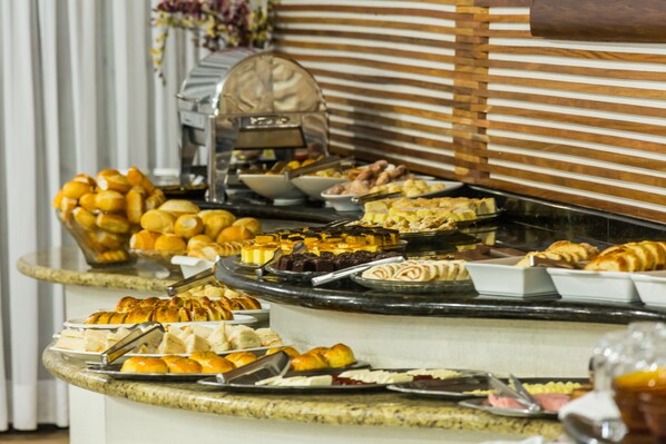 A buffet with various food items including pastries, fruits, and desserts.