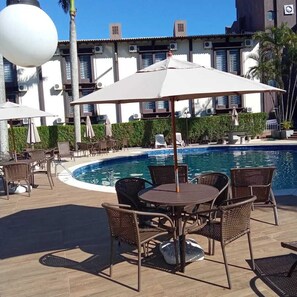 Una piscina al aire libre, sillones reclinables de piscina