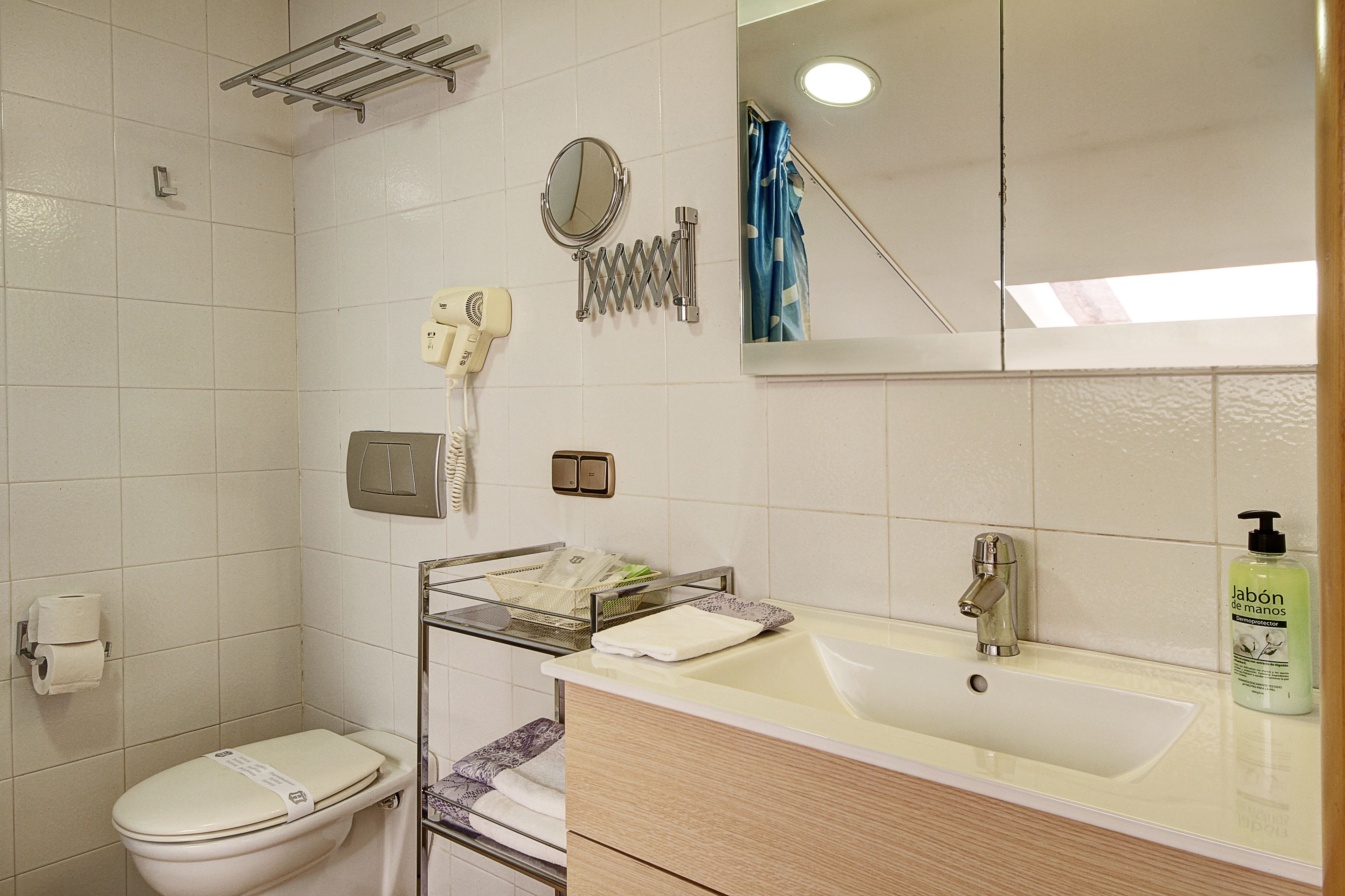Ein Badezimmer mit Toilette, Waschbecken, Spiegel, Handtuchhalter und einer Seife.