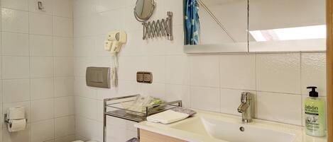 Ein Badezimmer mit Toilette, Waschbecken, Spiegel, Handtuchhalter und einer Seife.