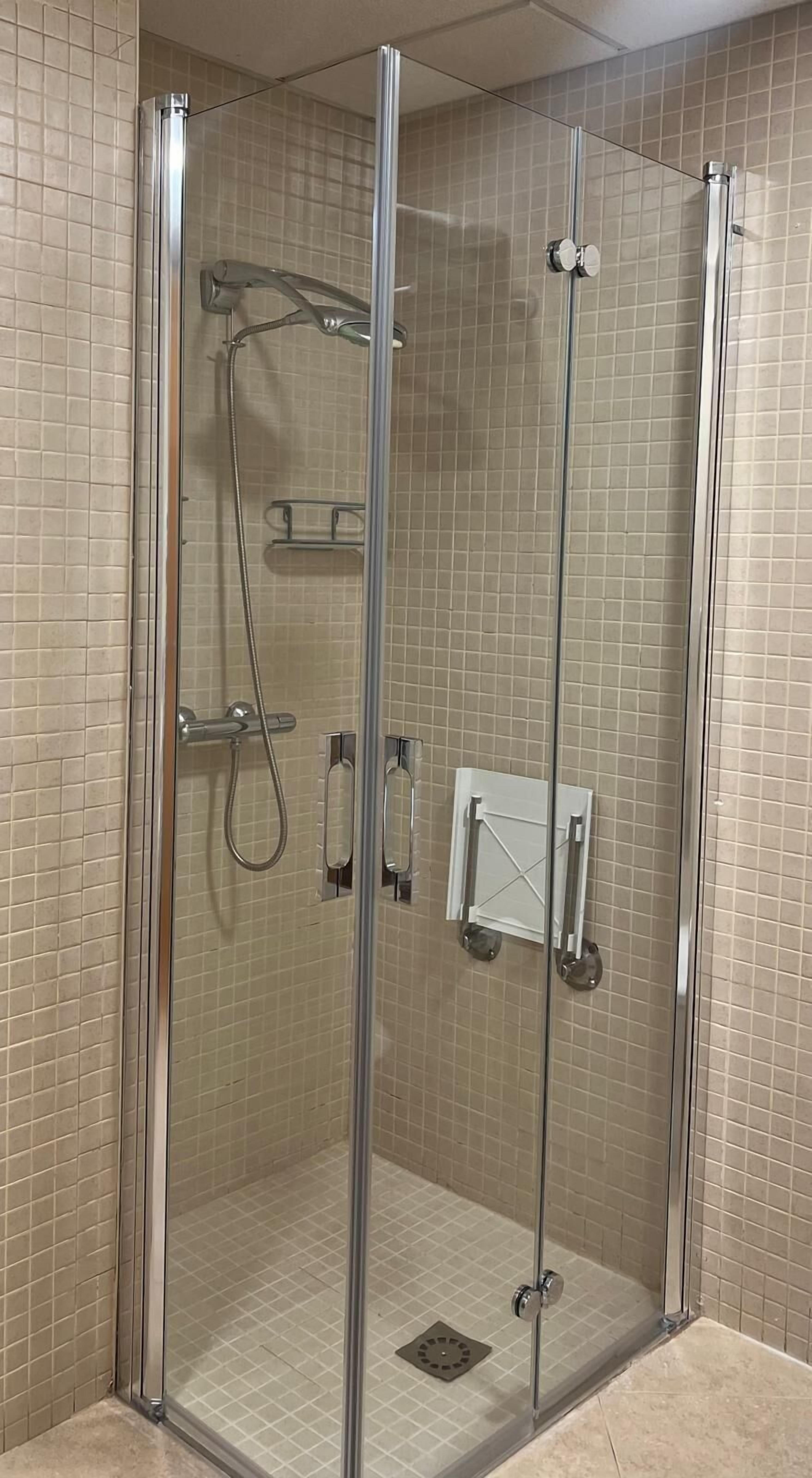 Cabina de dutxa amb vidre, sòl de rajoles i vàlvula de bany.