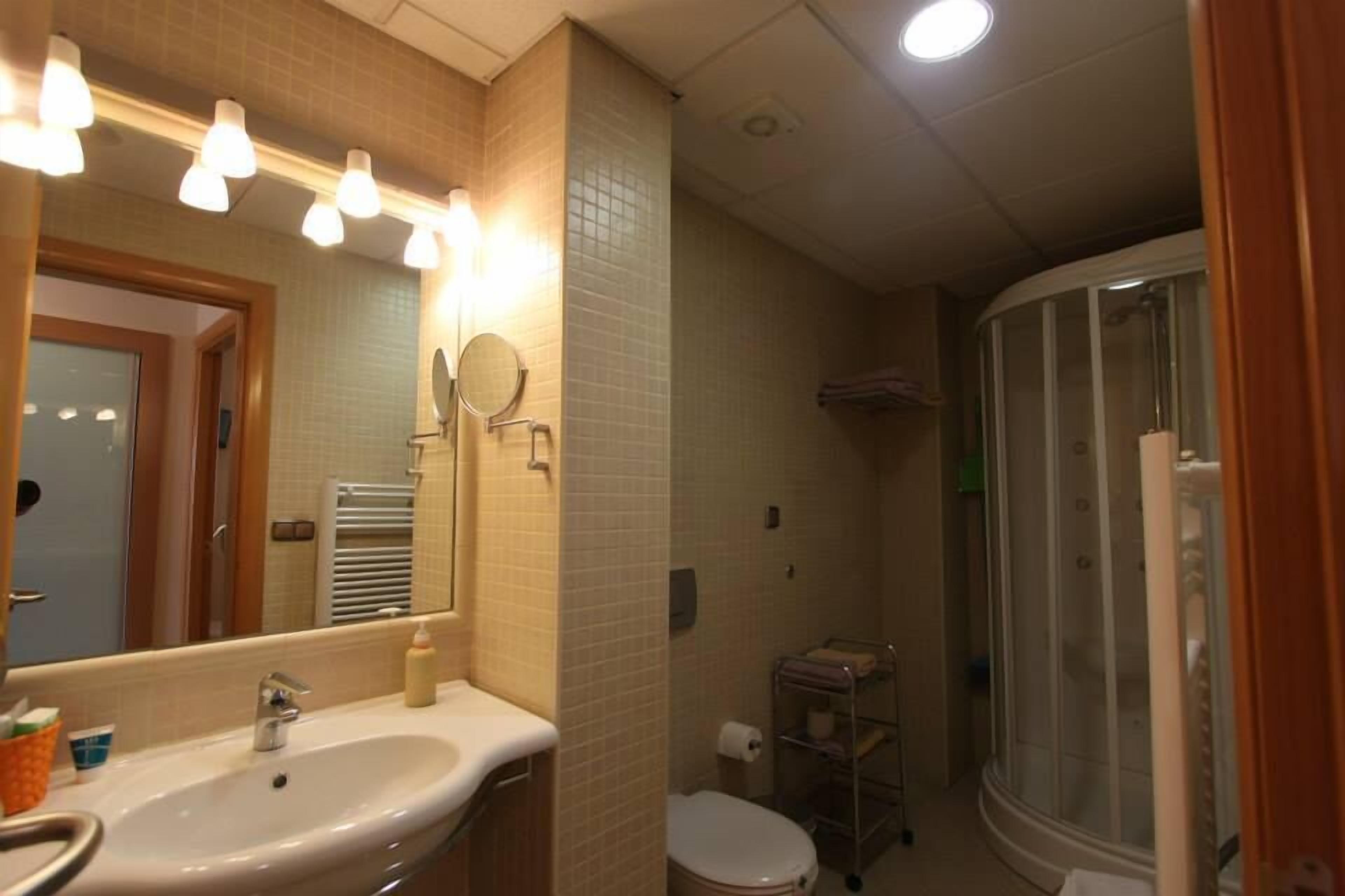 A bathroom with a sink, mirror, and shower.