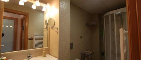 A bathroom with a sink, mirror, and shower.