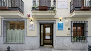 A building with a stone facade, a central entrance with a glass door, and signs for 'Centro' and 'AT Centro'. - Apartamentos Turísticos Centro (Granada)