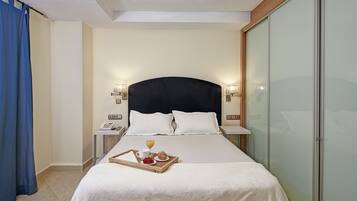 Habitación de hotel con una cama grande, lámparas de noche, teléfono junto a la cama y una bandeja con alimentos para el desayuno.