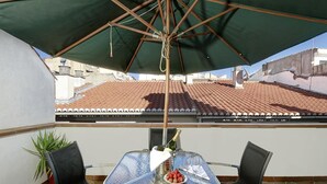 A balcony with a table, chairs, and a green umbrella. - Apartamentos Turísticos Centro (Granada)