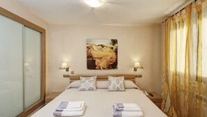 A hotel room with a large bed, two bedside lamps, a painting on the wall, and a curtain. - Apartamentos Turísticos Centro (Granada)
