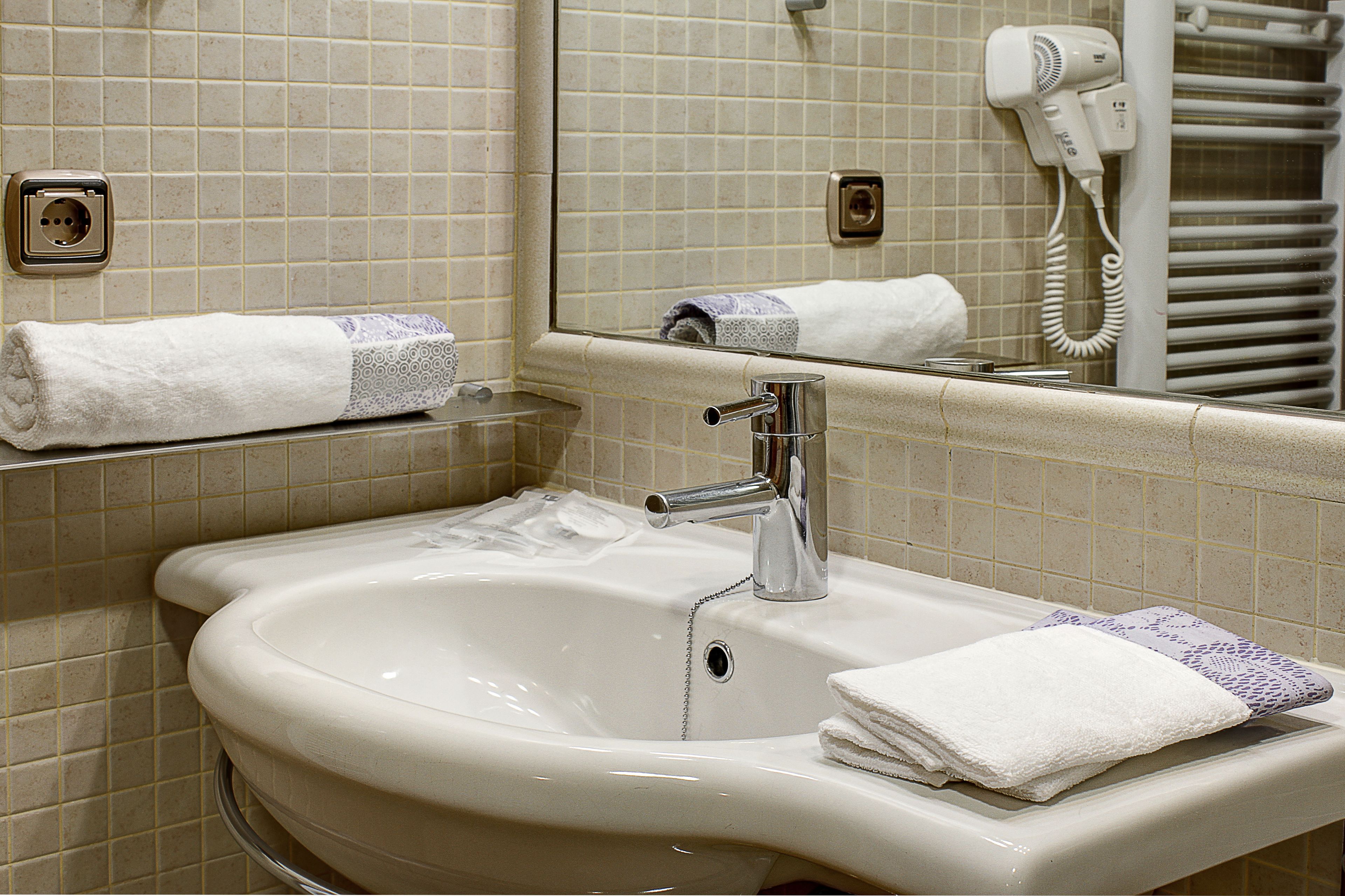 A bathroom with a sink, mirror, and towel rack.