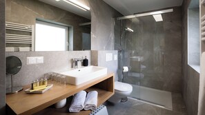 Ein modernes Badezimmer mit einem großen Waschbecken, einem Spiegel und einer Duschkabine aus Glas.