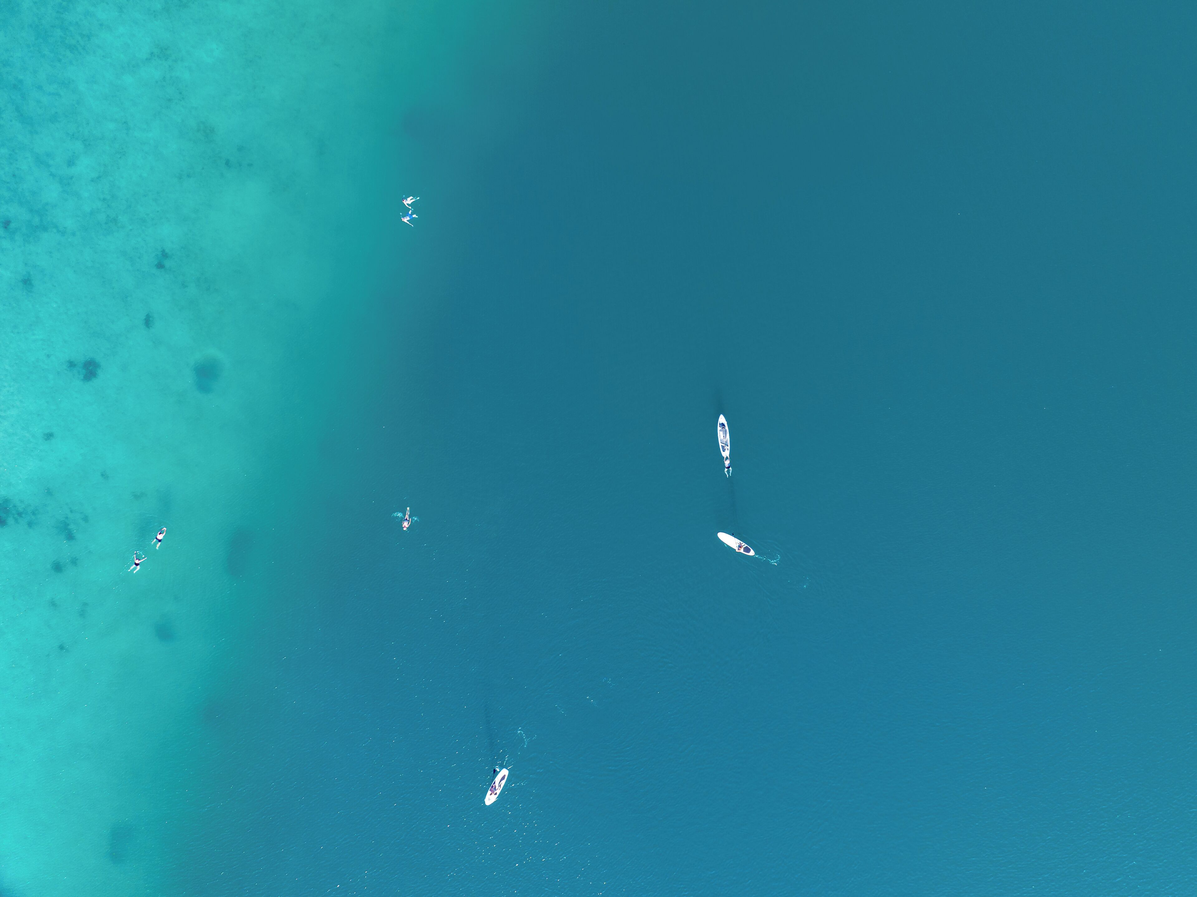Ein Luftbild einer Strandlandschaft mit klarem türkisblauem Wasser und mehreren Booten.