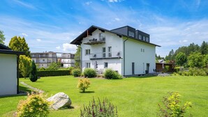 A modern two-story residential building with a balcony, surrounded by a well-maintained lawn and garden. - Apartments Jesse (Sankt Kanzian am Klopeiner See)