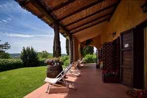 A covered outdoor area with a pergola, a row of sun loungers, and a view of the countryside. - B&B 8380 (Manciano)