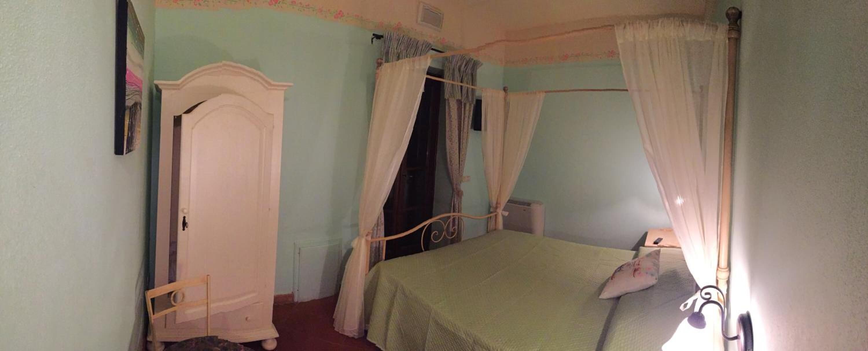 Una camera da letto con un letto a baldacchino, un'armadio in legno e una sedia.