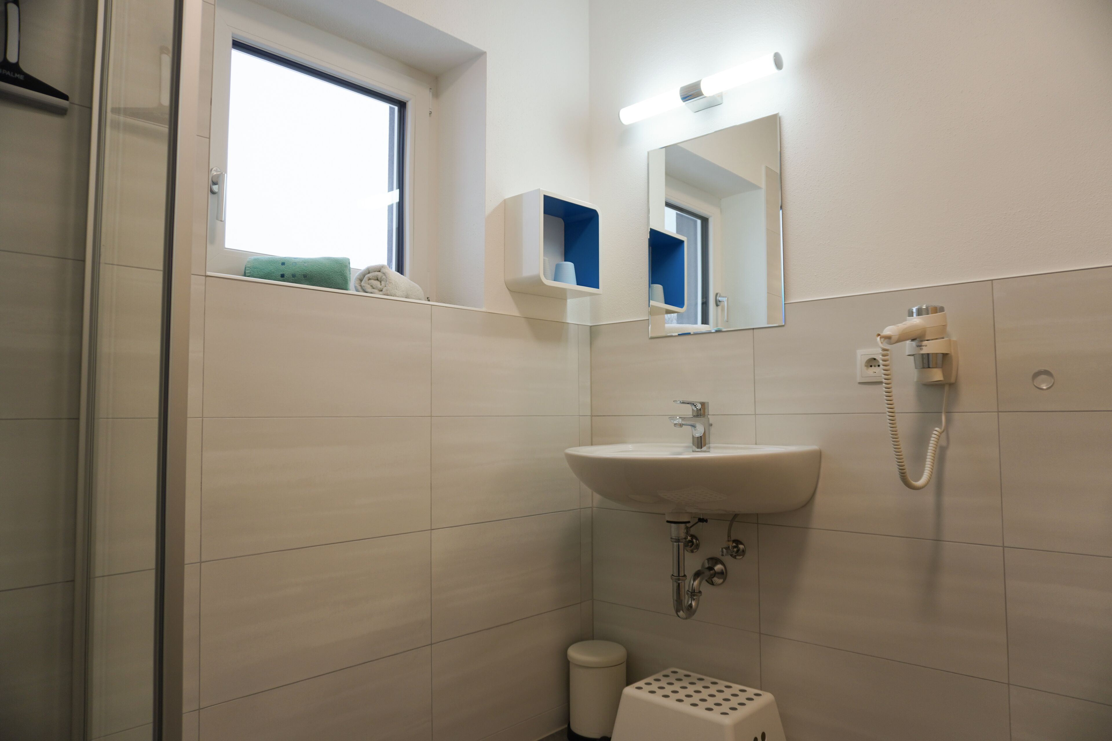A bathroom with a sink, mirror, and window.