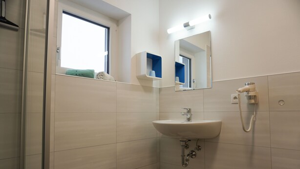 Une salle de bain avec un lavabo, un miroir et une fenêtre.