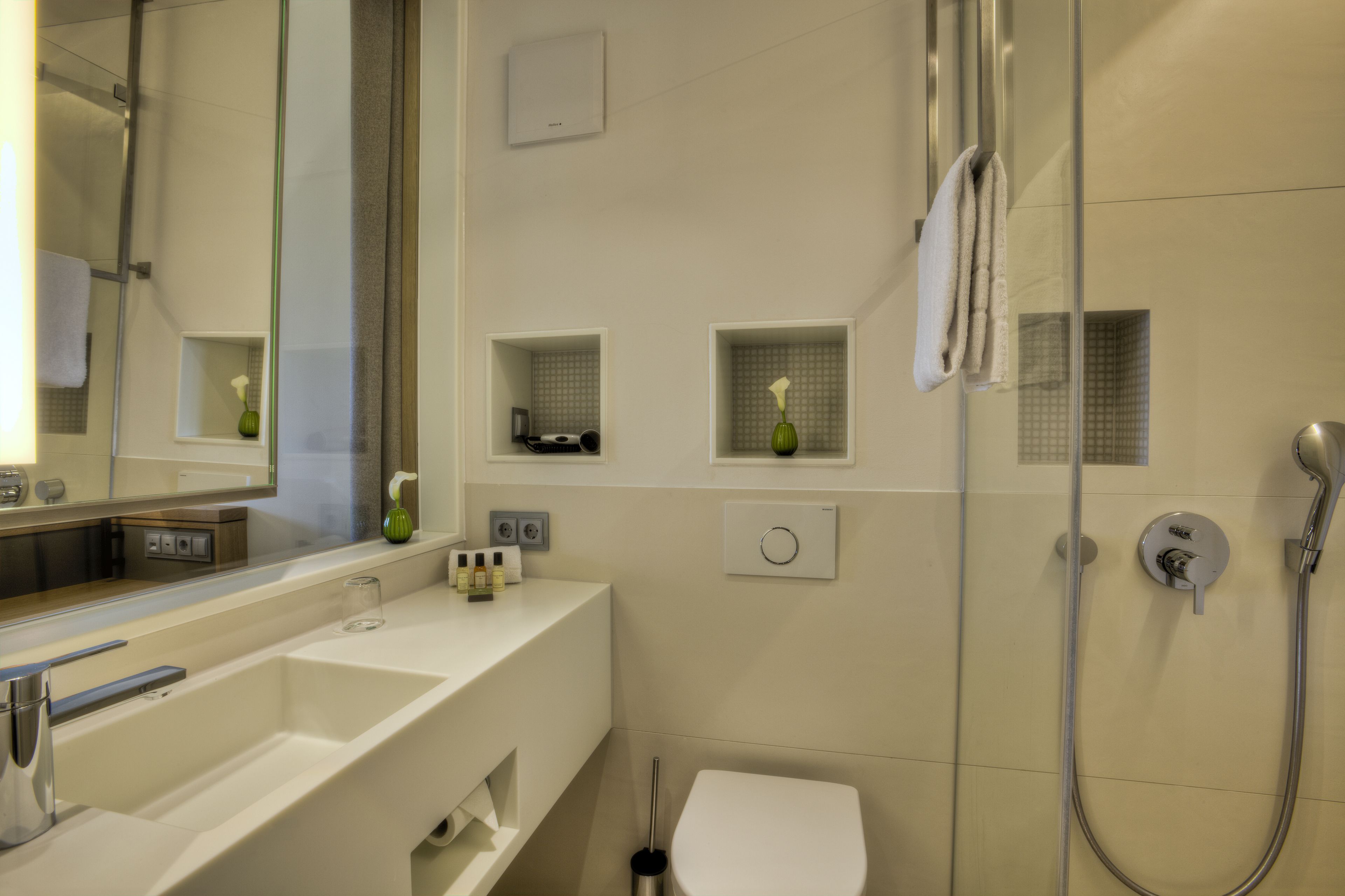 A modern bathroom with a large mirror, a sink, a toilet, and a shower area.
