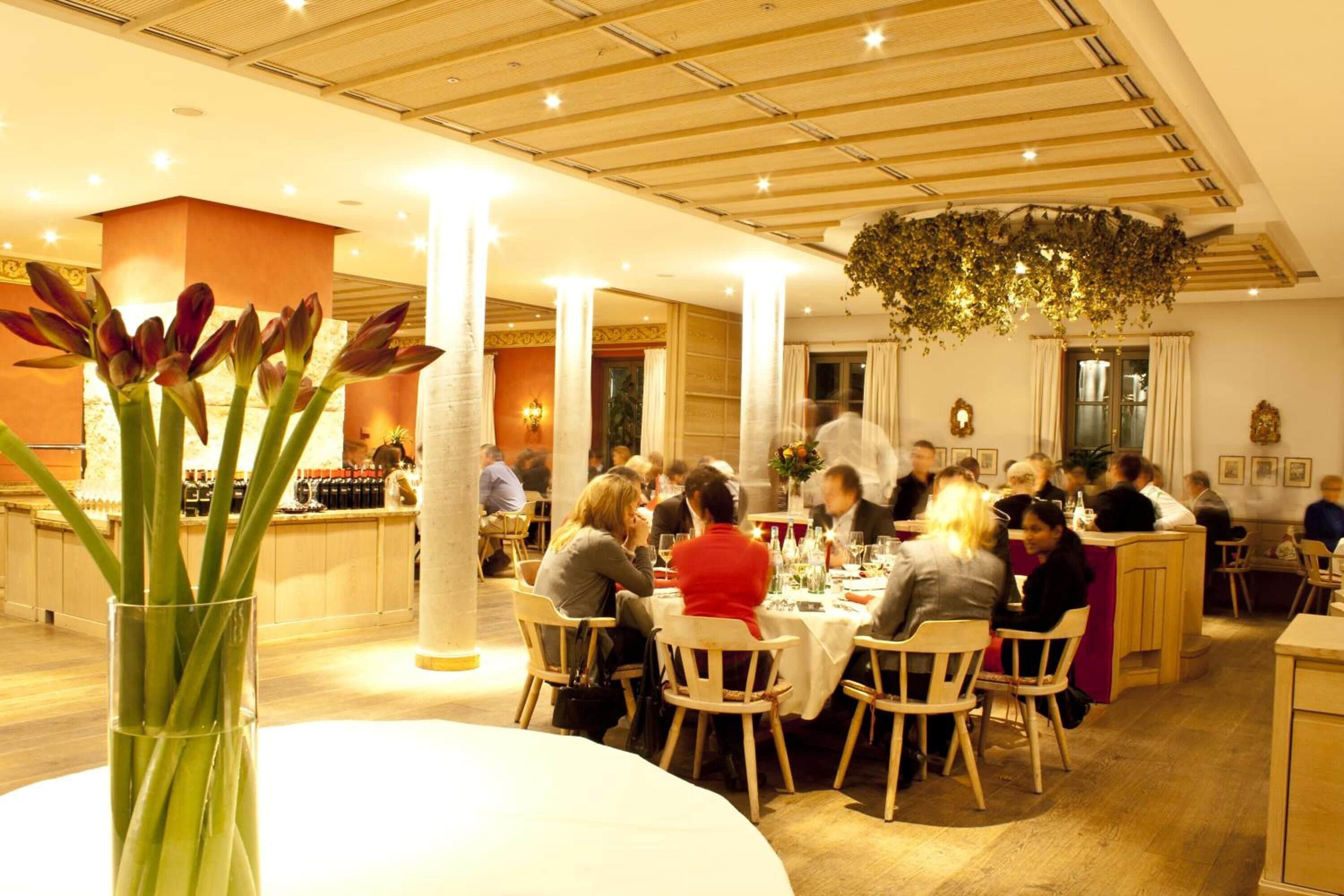 Un restaurant avec des tables et des chaises rondes, une colonne centrale et une plante suspendue.