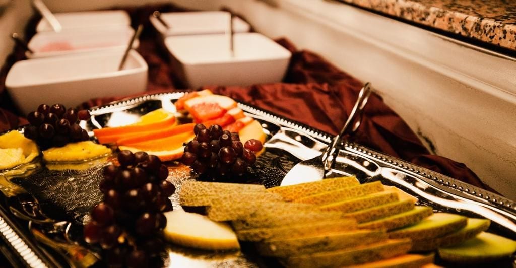 Un buffet con diverse pietanze, tra cui frutta, formaggi e pane.