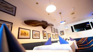 A dining area with tables, chairs, ceiling fans, and framed pictures on the walls.
