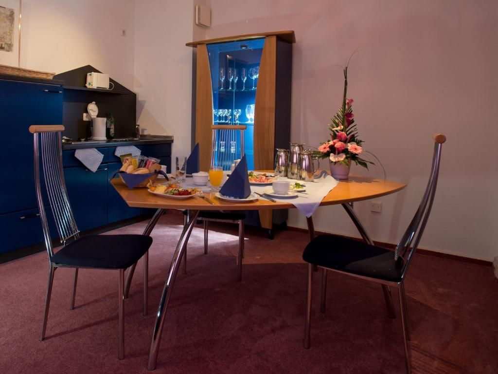 Un comedor con una mesa dispuesta para dos, un armario azul y una zona de bar con estantes.